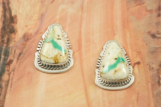 Genuine Boulder Turquoise set in Sterling Silver Post Earrings. The cabachons are of Boulder Turquoise, you can see the veins of Turquoise running through the host rock. The Boulder Turquoise Mine is located in northeast Nevada. It was discovered in 1970 by a Shoshone sheep herder. Production is small due to the remote location and winter weather. Boulder Turquoise is valued for both it's beauty and rarity. Every stone is unique. Created by Navajo Artist Arkie Nelson. Signed by the artist.